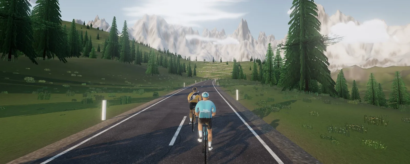 Two riders on an alpine road, one sitting in the other's draft